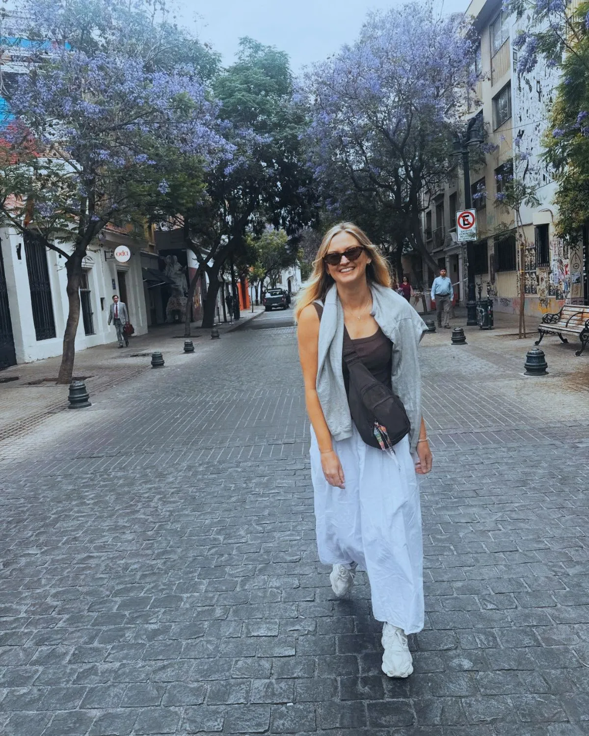 Jen walking through a tree-lined city street while travelling