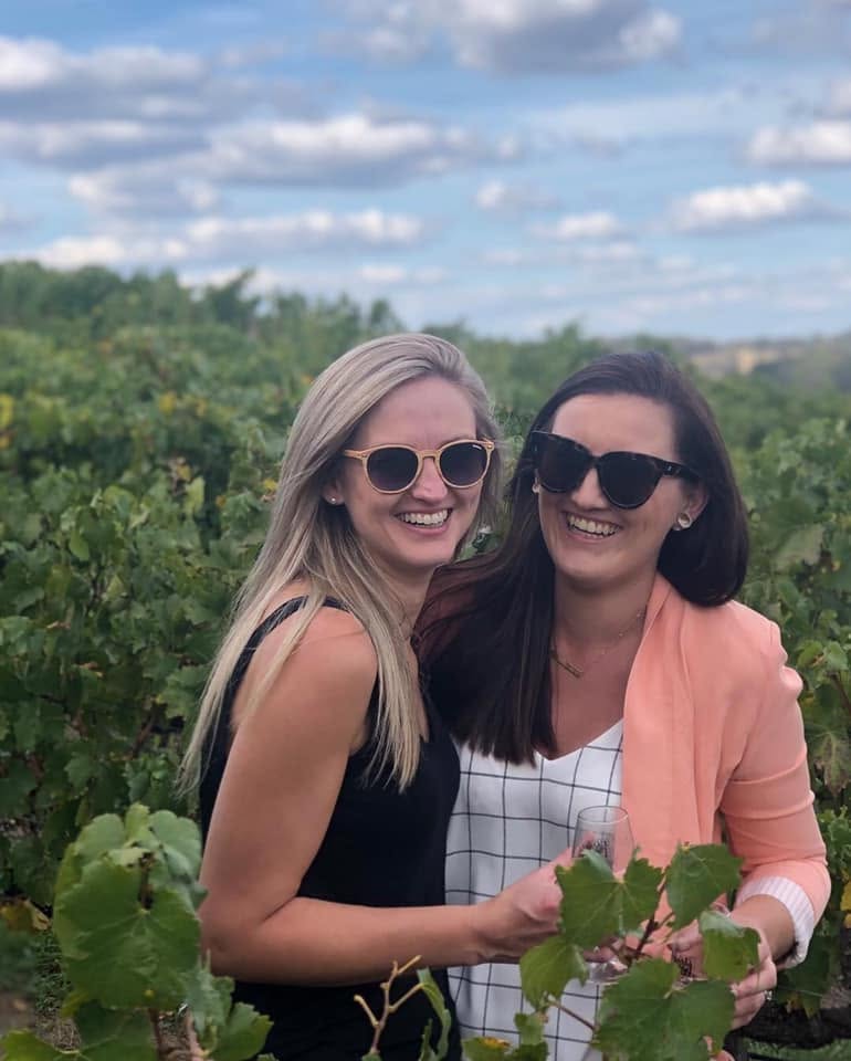 Jen and a friend together among vineyard rows in Orange