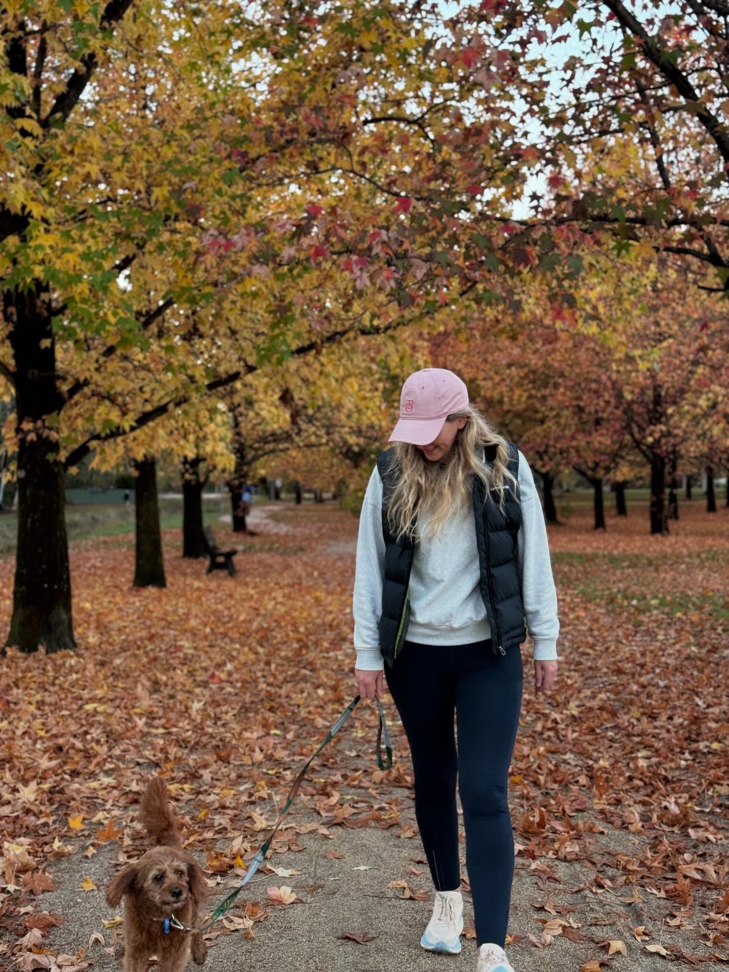 Jen walking her dog beneath autumn trees in Orange